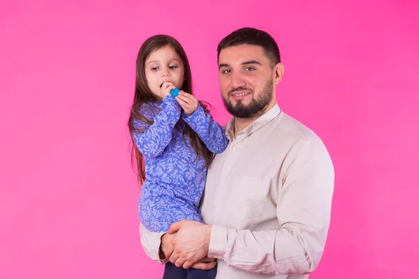 Feliz padre sosteniendo bebé hija en manos sobre rosa fondo — Foto de Stock