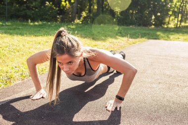 Fitness kadın açık çapraz eğitim egzersiz sırasında şınav. Güzel genç ve formda fitness spor modeli eğitim dışında park