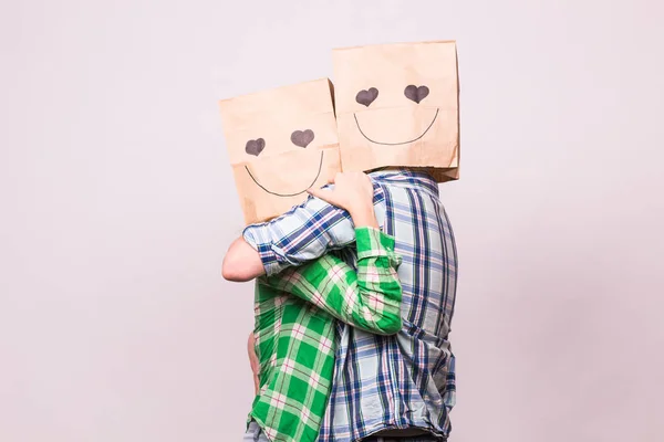 Amor pareja cubriendo sus caras con bolsa de papel sobre fondo blanco — Foto de Stock