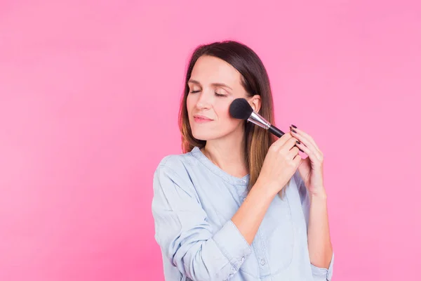 Artista de maquillaje profesional con pinceles sobre fondo rosa — Foto de Stock