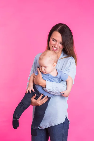 Feliz joven madre con un bebé niño sobre fondo rosa — Foto de Stock