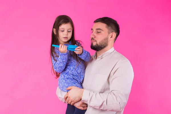 Feliz padre sosteniendo bebé hija en manos sobre rosa fondo — Foto de Stock