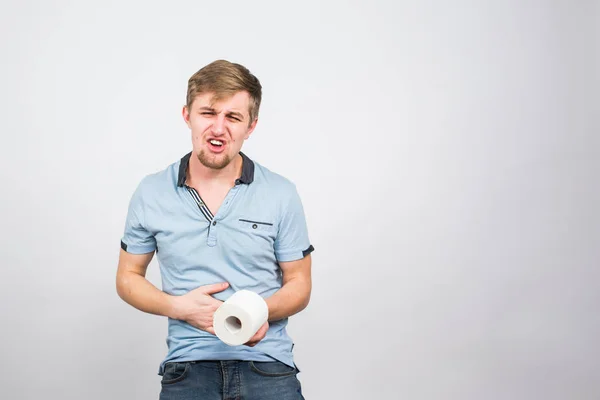 Άνθρωπος με πόνο στο στομάχι και ρολό χαρτί τουαλέτας σε λευκό φόντο — Φωτογραφία Αρχείου