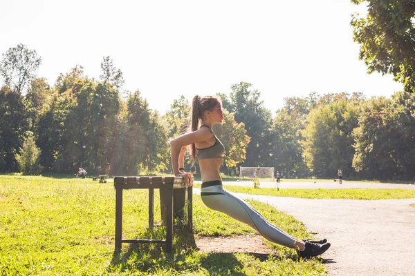 Young fit woman exercising by doing push-ups outdoors — Stock Photo, Image