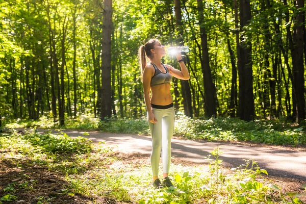 Deportiva mujer bebiendo agua al aire libre en día soleado. — Foto de Stock