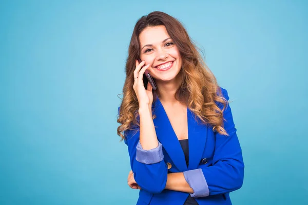 Feliz sonriente exitosa mujer de negocios con teléfono celular, sobre fondo azul — Foto de Stock