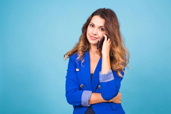Fiatal mosolygó üzleti nő beszél ó a telefon, a kék háttér — Stock Fotó