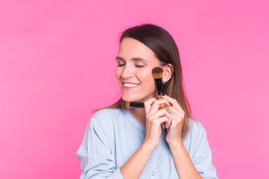 Pembe bir arka plan üzerinde fırçalar ile profesyonel makyaj sanatçısı