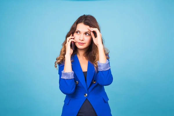 Hermosa joven habla hablando por teléfono móvil sobre un fondo azul — Foto de Stock