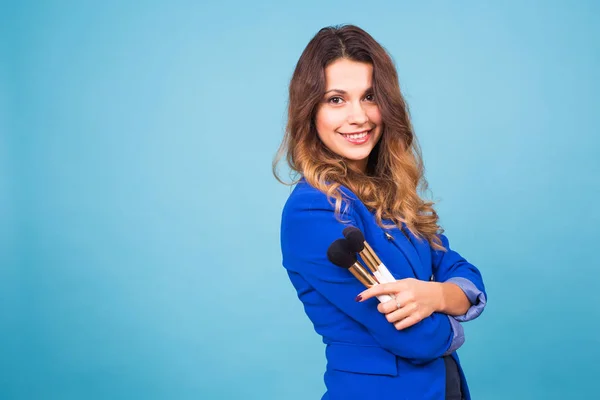 Primer plano retrato de maquillador con pinceles sobre fondo azul — Foto de Stock