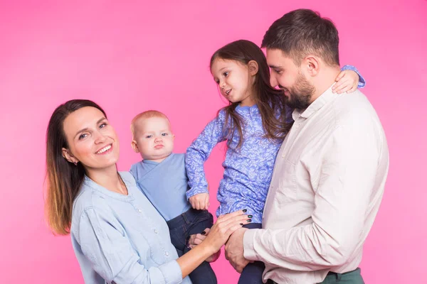 Linda familia posando y sonriendo a la cámara juntos sobre fondo rosa — Foto de Stock