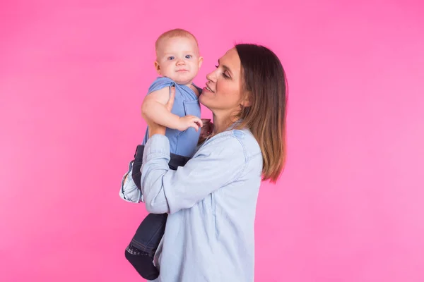 Feliz joven madre con un bebé niño sobre fondo rosa — Foto de Stock