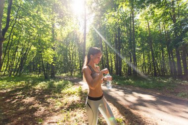 Açık havada koşu sonra genç kadın içme suyu