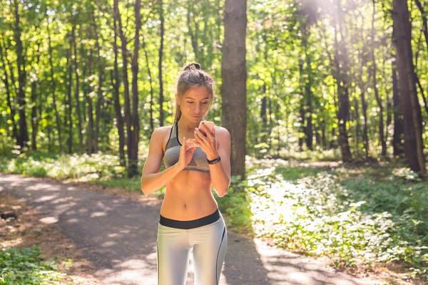 Молода спортсменка перевіряє прогрес фітнесу на своєму смарт-годиннику. Жінка бігунка використовує фітнес-додаток для моніторингу продуктивності тренування . — стокове фото