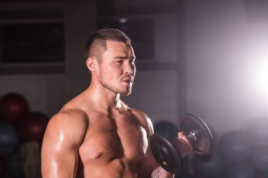 Spor salonunda spor yapan kaslı bir adam, pazularıyla egzersiz yapıyor. Güçlü erkek, çıplak karın kasları var..