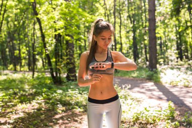 Etkinlik izleyicisi'ni veya kalp atış hızı monitörünü kullanan kadın. Açık alan fitness kavramı.