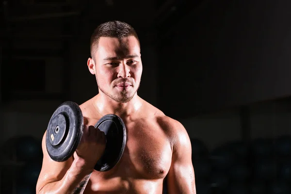 Svalnatý muž cvičení v tělocvičně s činky na biceps, silné mužské nahý trup abs. — Stock fotografie