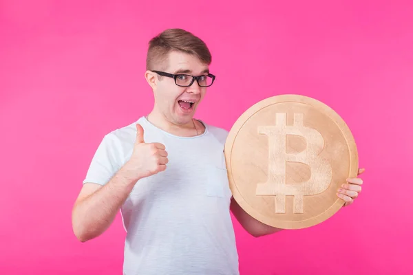 Joven feliz sosteniendo gran bitcoin de oro sobre fondo rosa. Cripto moneda, dinero virtual, internet y concepto de economía — Foto de Stock
