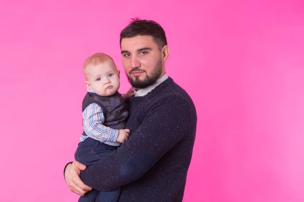 Feliz padre sosteniendo bebé hijo en manos sobre fondo rosa — Foto de Stock