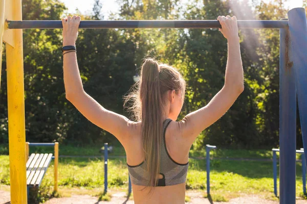 Kobiety fitness lekkoatletycznego młody, ćwicząc w siłowni odkryty, pull up o wschodzie słońca. — Zdjęcie stockowe