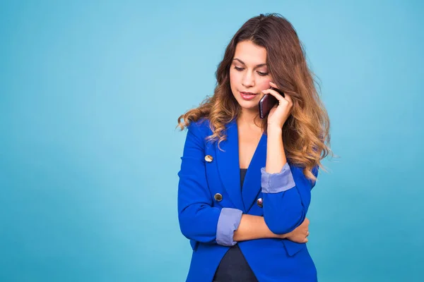 Fiatal mosolygó üzleti nő beszél ó a telefon, a kék háttér — Stock Fotó