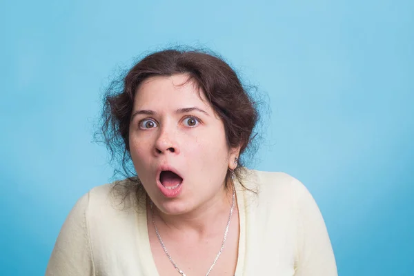 Jeune femme avec une expression choquée et étonnée sur fond bleu — Photo