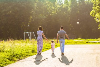 Mutlu aile açık hava etkinliği. Anne ve bebek kızı eğleniyor ve yaz Park'ta yürüyordunuz arkadan görünüş.