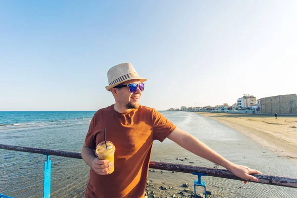 Hombre con frappe de café mirando el mar sintiéndose libre disfrutando de vacaciones de tiempo libre — Foto de Stock
