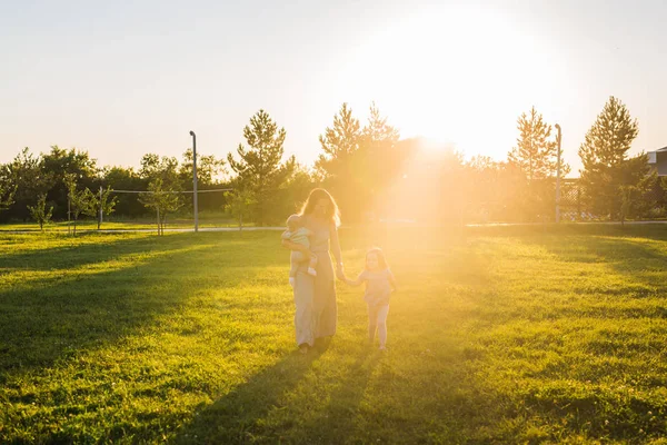 夏の日当たりの良い公園を歩いて少しの娘と赤ちゃんの息子の母 — ストック写真