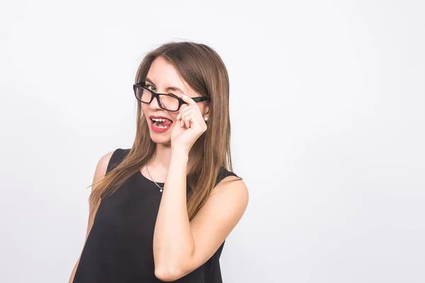 Молода жінка в окулярах посміхається і підморгує на білому тлі — стокове фото