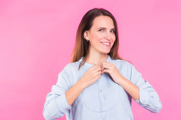 Lachende vrouw in hemd poseren in studio op roze achtergrond — Stockfoto