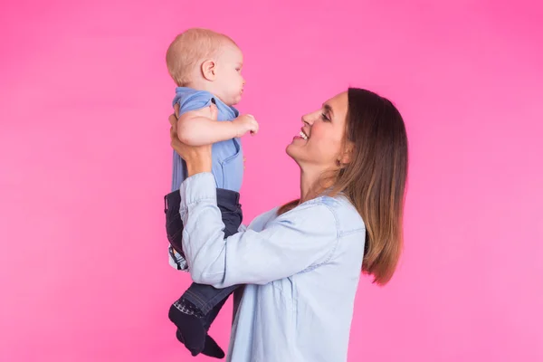 Madre cariñosa jugando con su bebé sobre fondo rosa — Foto de Stock