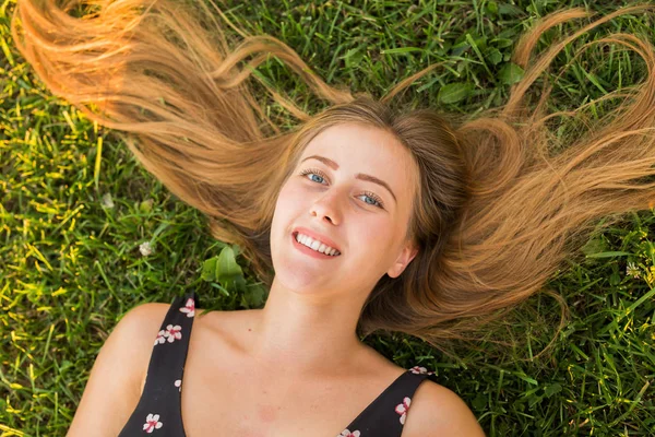Vista superior de uma mulher relaxada feliz deitada na grama verde e sorrindo . — Fotografia de Stock