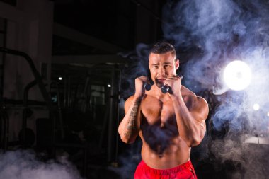 Boks egzersizleri yapıyorsun, tam isabet dumbbells ile güçlü bir adam. Sportif kaslı erkek fotoğrafı. Güç ve motivasyon