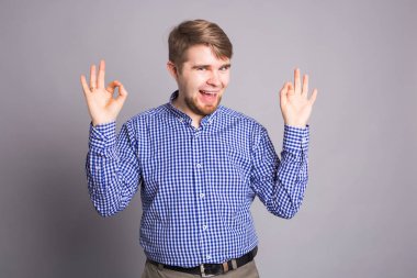 İyimser genç gri arka planda gösterilen içeriği ve mutluluk olumlu duygular ile ok. Kalite ve tavsiye ile memnuniyetini kavramı