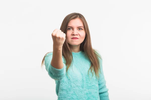 Joven morena furiosa muestra puño. La chica está muy enojada y lista para usar sus puños. Emociones agresivas negativas en su cara . — Foto de Stock