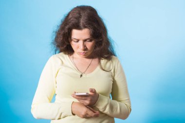 Mavi arka plan üzerinde cep telefonu kullanan kadın