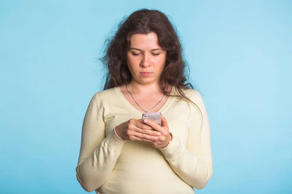 Mujer usando teléfono celular sobre fondo azul —  Fotos de Stock