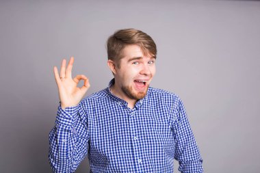 İyimser genç gri arka planda gösterilen içeriği ve mutluluk olumlu duygular ile ok. Kalite ve tavsiye ile memnuniyetini kavramı