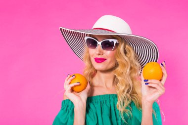 Güzel şık kadın güneş gözlüğü ve şapka ile portakal pembe arka plan üzerinde eğleniyor. Yaz, tatil ve moda kavramı