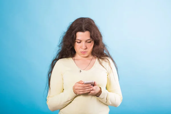 Mulher usando celular no fundo azul — Fotografia de Stock