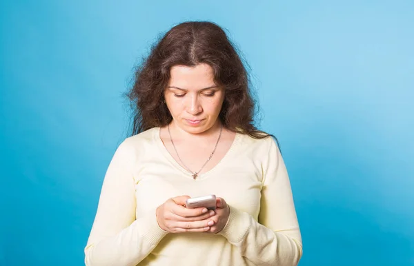 Mavi arka plan üzerinde cep telefonu kullanan kadın — Stok fotoğraf