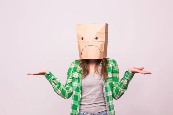 Mujer infeliz con emoticono triste delante de la bolsa de papel en la cabeza sobre fondo blanco — Foto de Stock