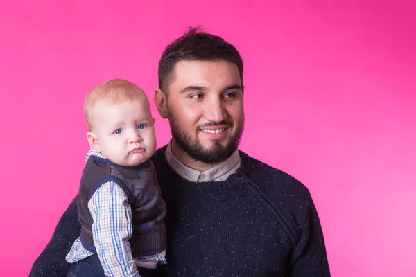 Retrato de padre feliz con un hijo pequeño aislado sobre un fondo rosa — Foto de Stock