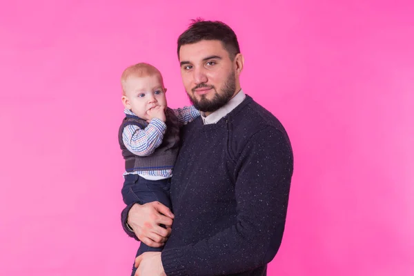 Padre feliz con su hijo bebé sobre fondo rosa — Foto de Stock