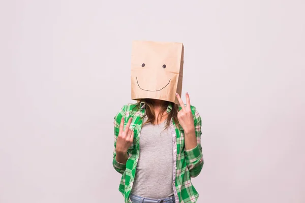 Mujer desconocida feliz con una bolsa de papel en la cabeza sobre fondo blanco —  Fotos de Stock