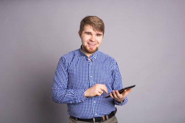 Gri arka plan üzerinde tablet kullanan adam.