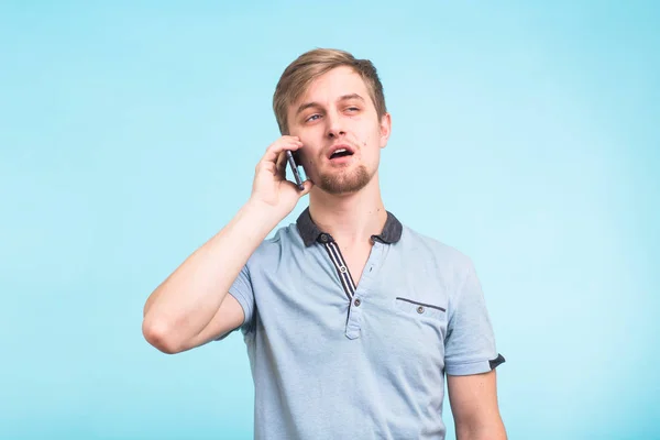 파란색 배경 위에 전화 통화 하는 젊은 남자의 초상화 — 스톡 사진