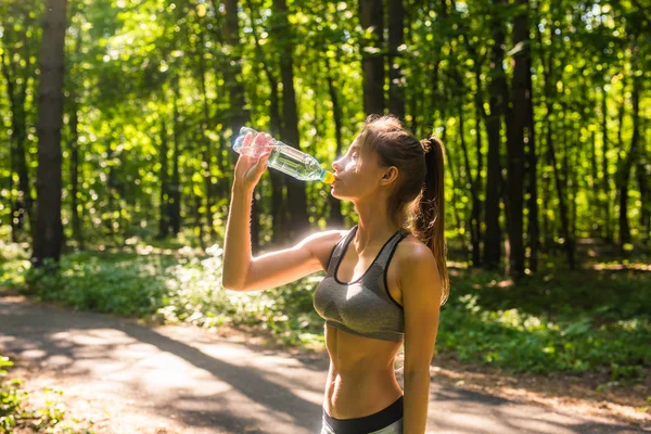 Jeune femme boire de l'eau après le jogging à l'extérieur — Photo
