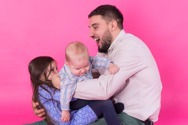 Vater mit Kindern hat Spaß auf rosa Hintergrund — Stockfoto